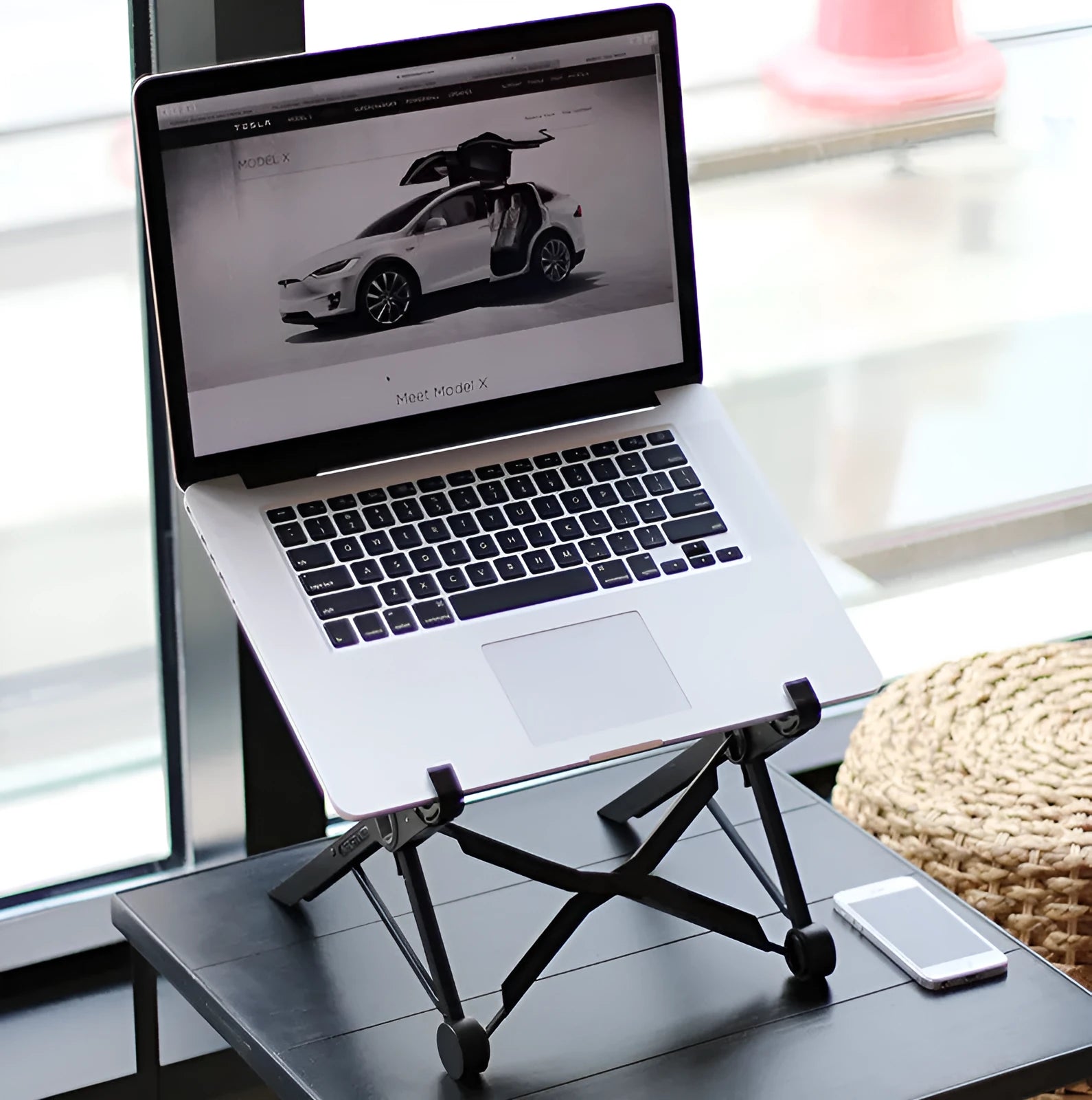 Black folding portable laptop stand made of reinforced nylon, shown folded and unfolded.
