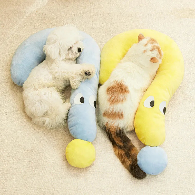 A rectangular blue pet sleeping pillow on a floor, shown next to a small dog for scale.