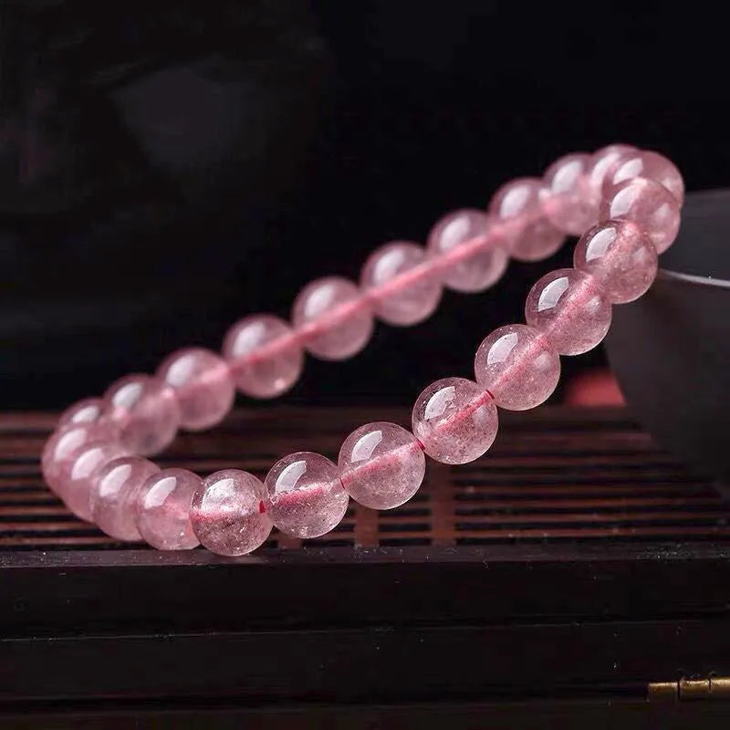 Women's strawberry quartz crystal bracelet showing polished beads in 6mm, 8mm, and 10mm size options