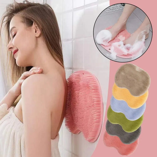 Orange suction cup bath brush with silicone bristles for foot and back cleaning on a bathroom floor.