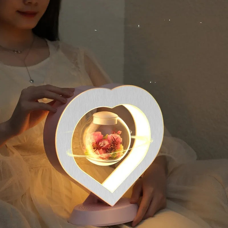 Floating heart LED night light with magnetic levitation displaying a red eternal flower on a desk