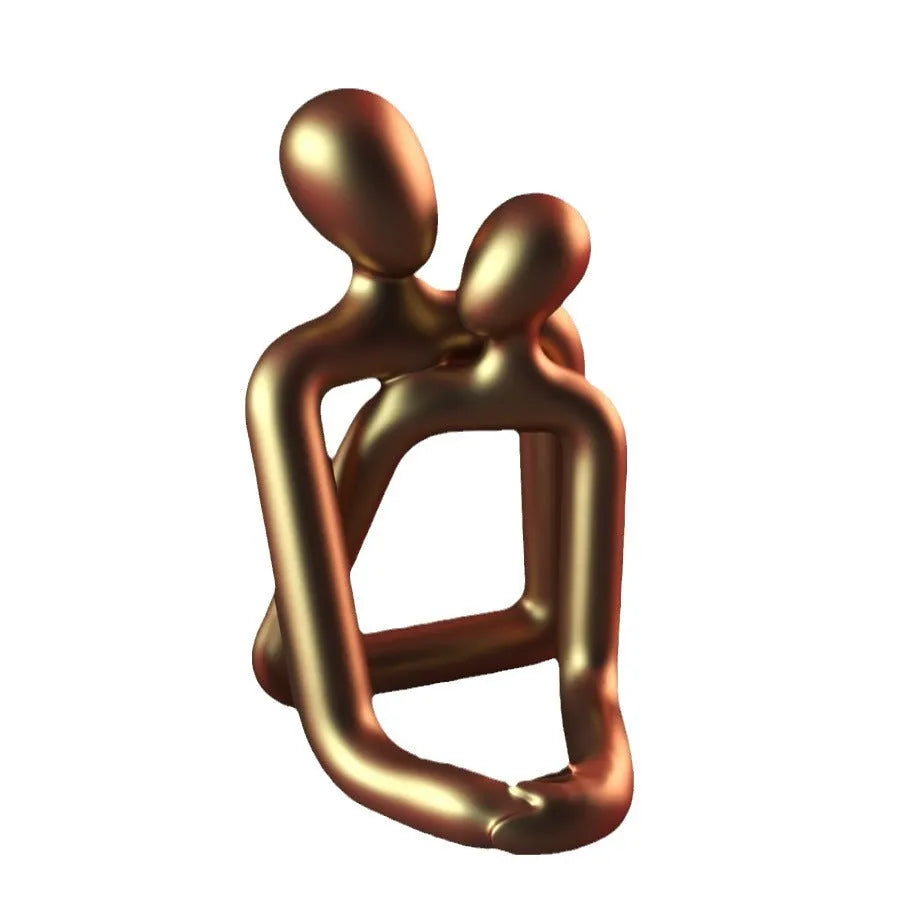 Modern loving couple resin statue in gold or milky white on a wooden shelf.
