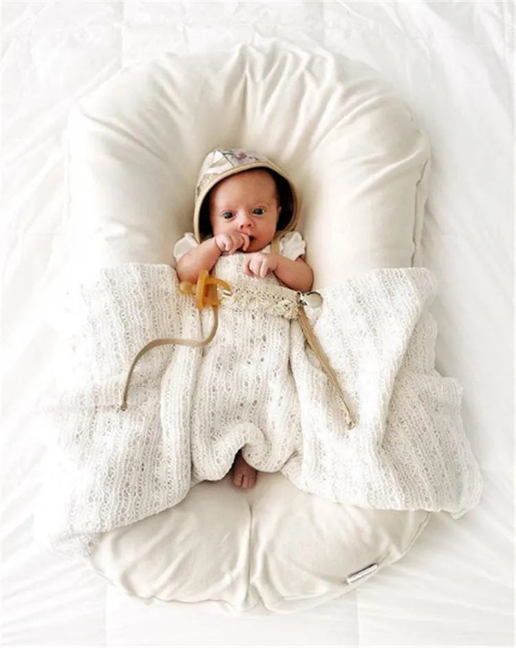 Beige portable cotton baby nest crib for newborns measuring 75cm by 45cm on a neutral background