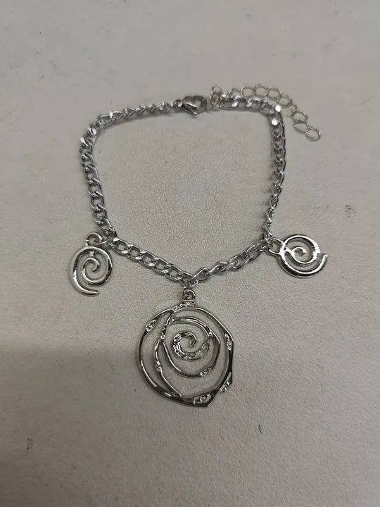 Gold spiral donut design necklace, bracelet, and earrings set on a grey background.