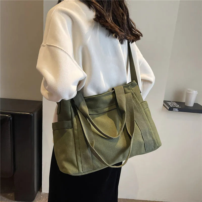 Large black polyester canvas shoulder tote bag showing outer sandwich pocket.