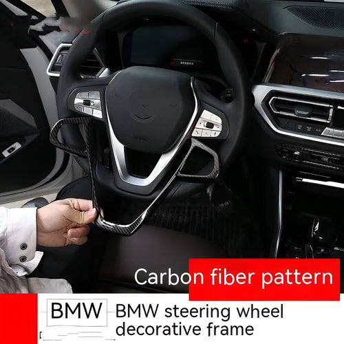 Black carbon fibre pattern button frame decoration for a BMW steering wheel.