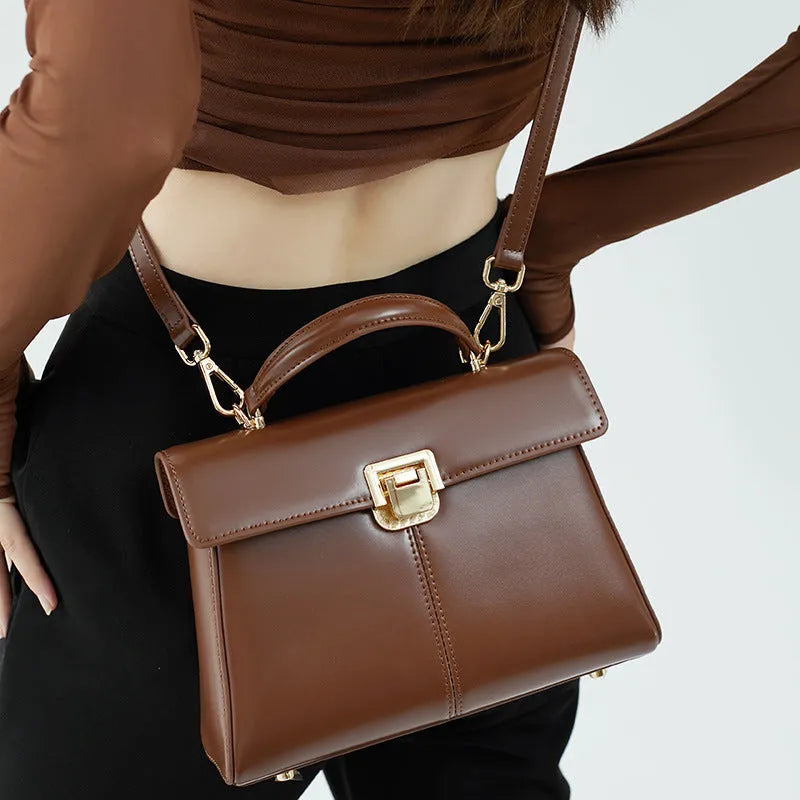 Women's black genuine leather shoulder bag with gold clasp closure showing interior compartments