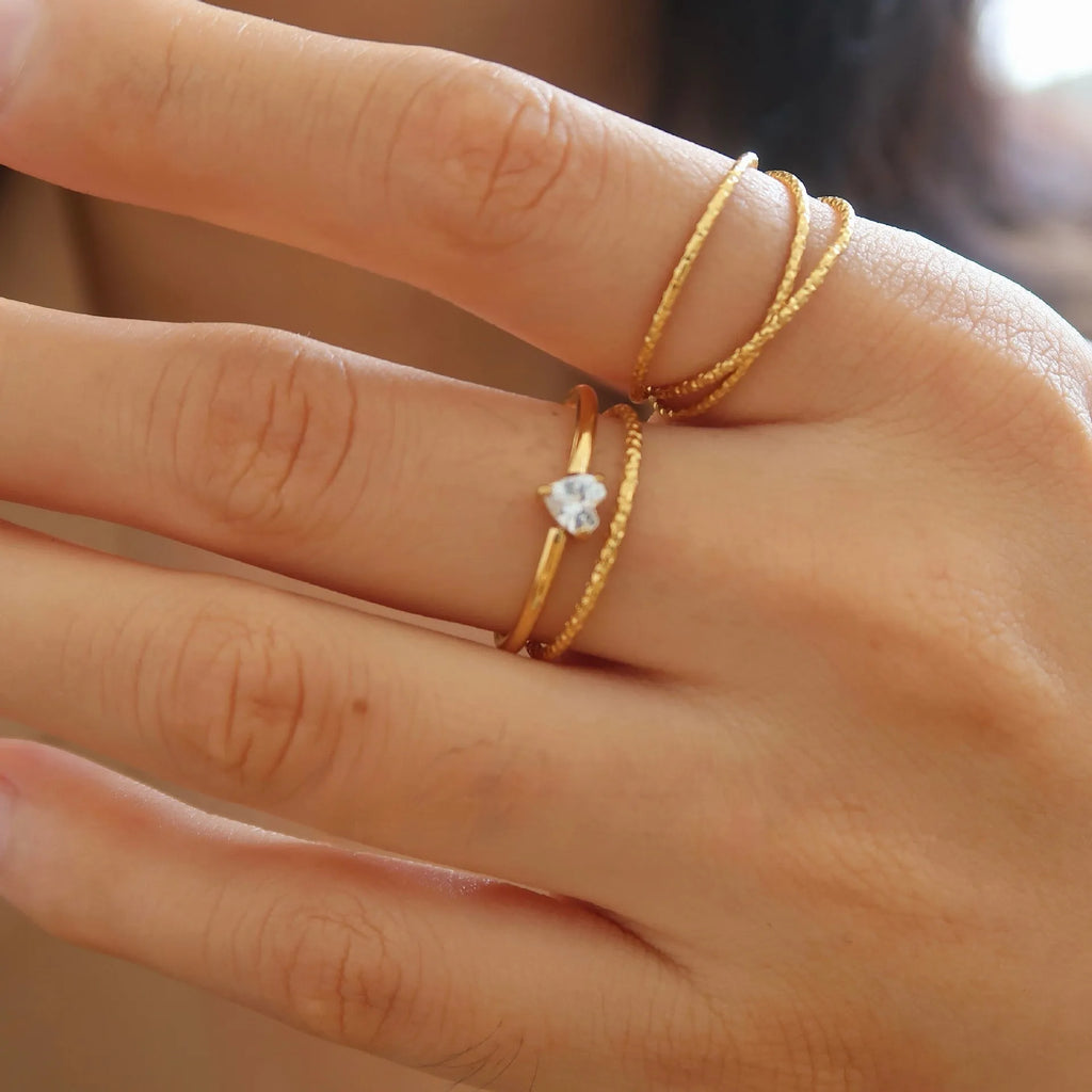 Golden stainless steel ring showing heart and oval love symbol designs with size options from 5 to 8