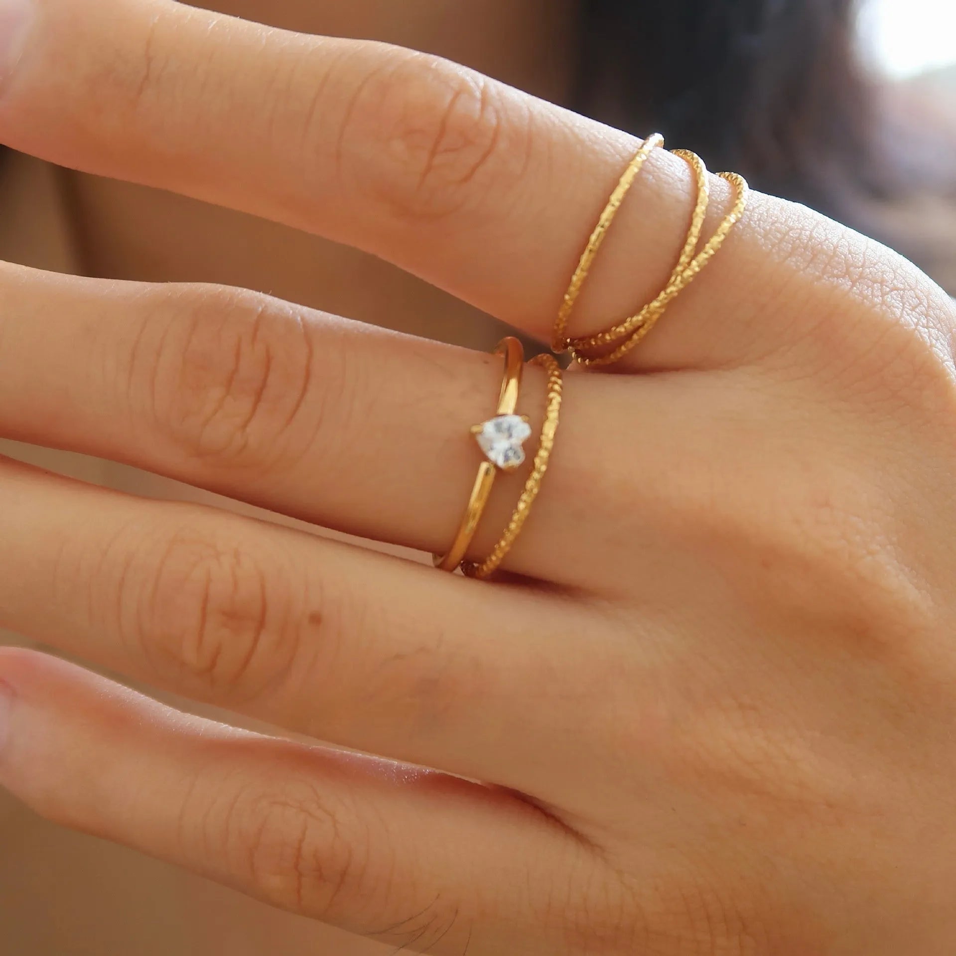 Golden stainless steel ring showing heart and oval love symbol designs with size options from 5 to 8