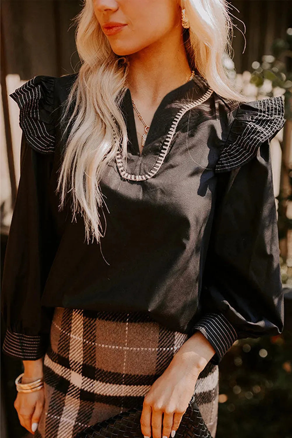 Black women's V-neck blouse with long ruffle-trimmed sleeves and contrast stitching