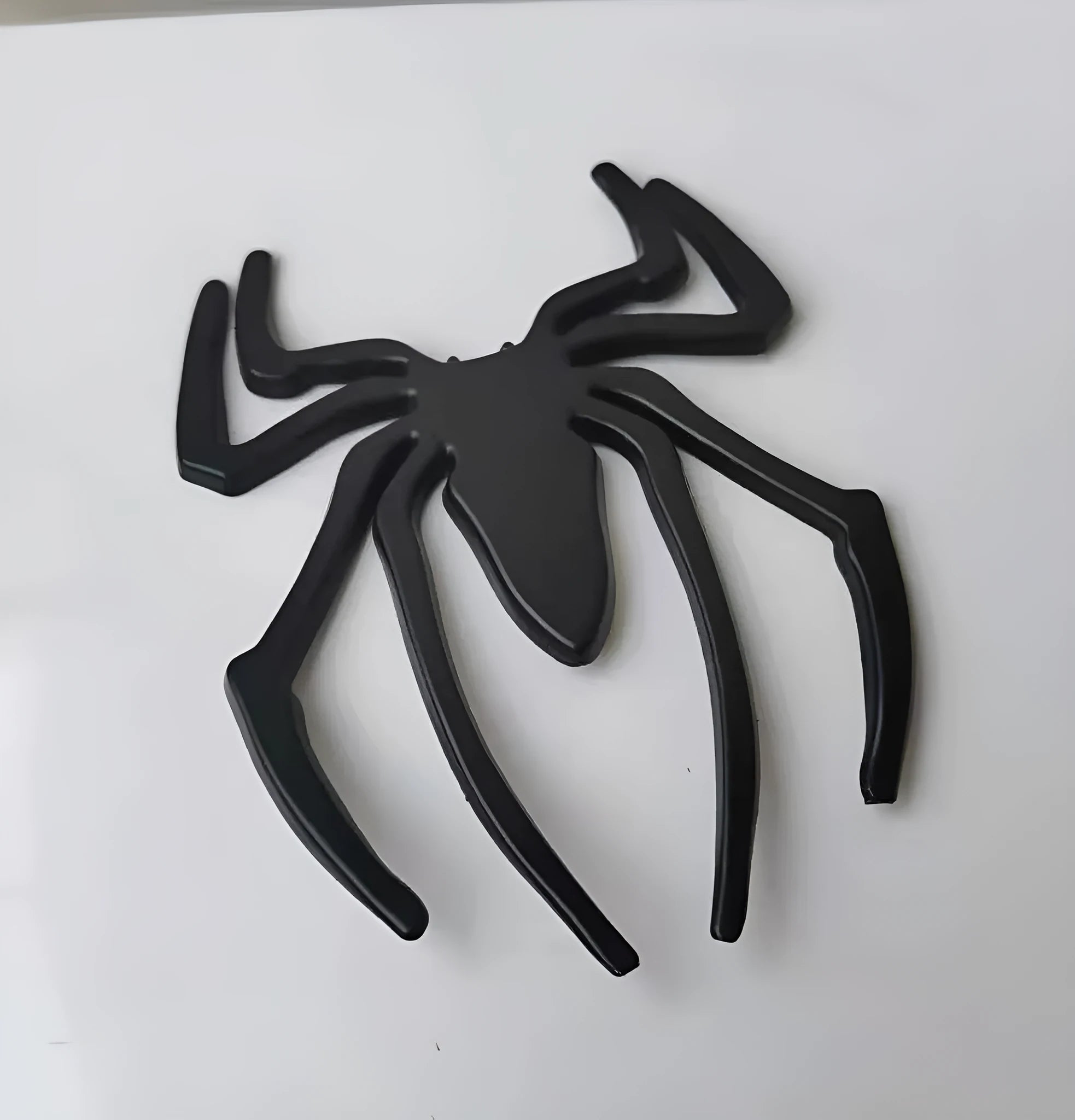 Three-dimensional metal spider bumper sticker in zinc alloy, shown in gold colour.
