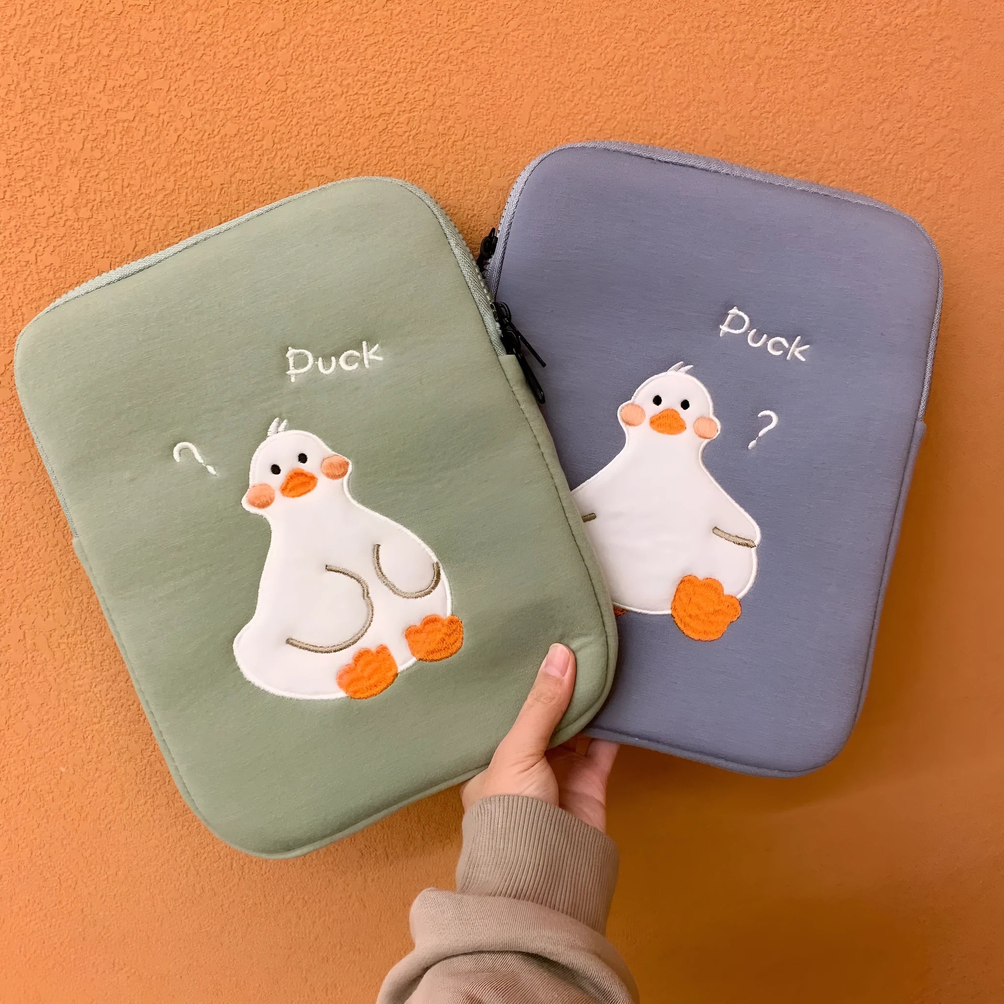 Blue cotton tablet case with embroidered cartoon duck design and a zipper.