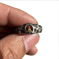 Hand-forged copper Grotto Buddha ring with a rock-textured surface, shown on a size 8 finger.