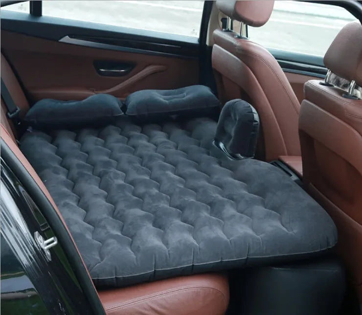 Black inflatable car bed with flocking surface and two pillows, shown folded next to a storage bag.