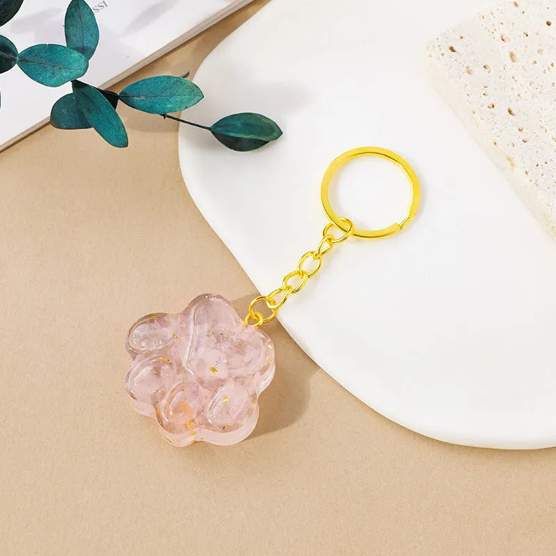 Natural crystal cat's paw shaped keychain charm on a keyring, showing colour variations of different gemstones.