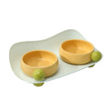 A pink ceramic raised pet bowl with two compartments and a non-slip black rubber base.