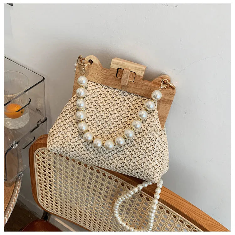 Women's straw woven shoulder bag with pearl chain strap in horizontal square shape showing internal organisers
