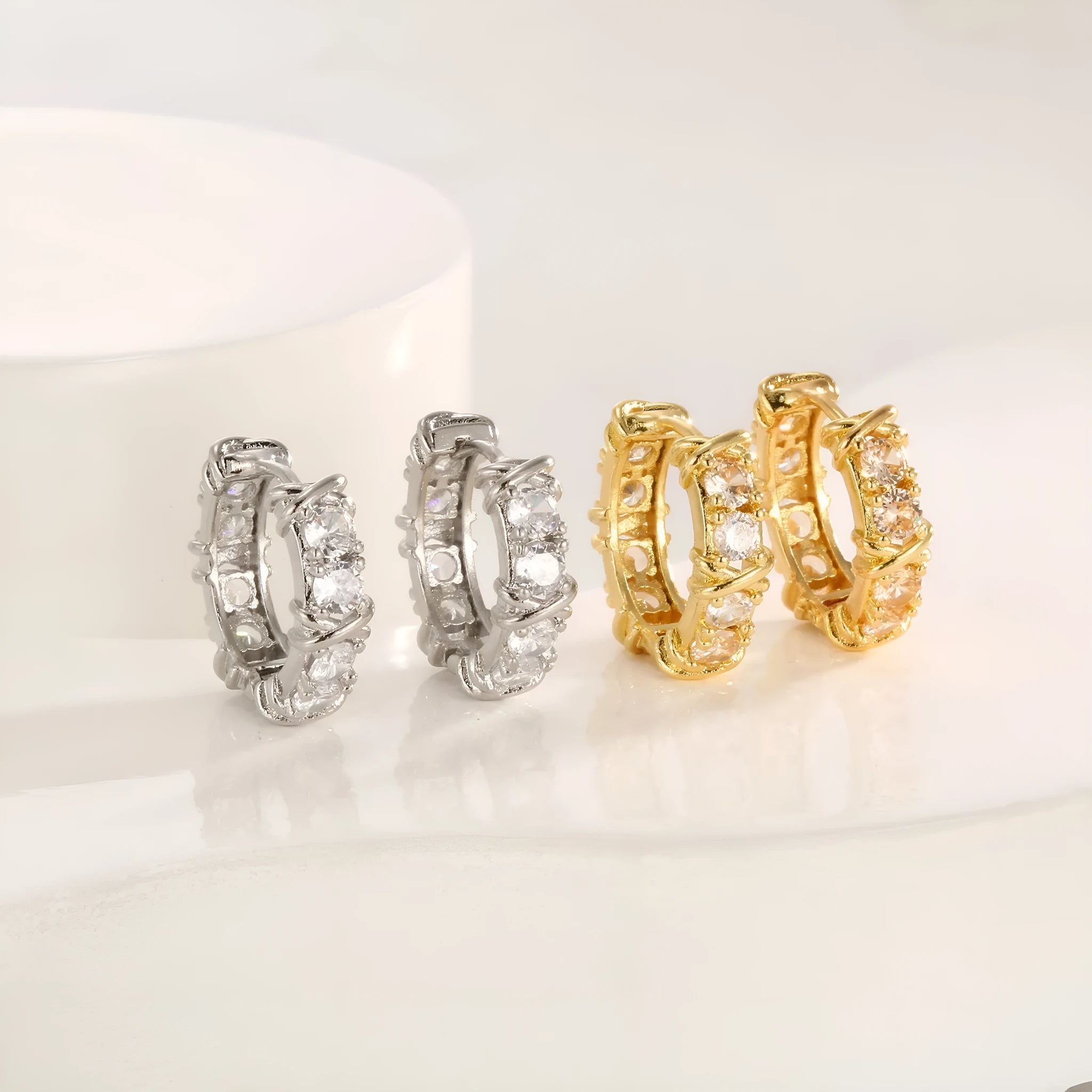 A pair of geometric clover cross earrings with a hexagonal shape in a silver or gold electroplated finish.