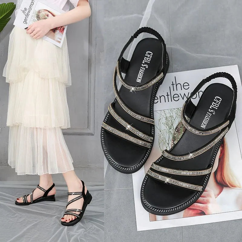 Women's flat sandals in gold with round toe, rhinestone decoration, and elastic band.