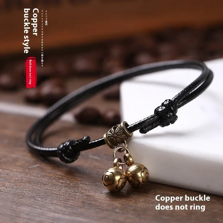 Close-up of a black nylon rope dog collar for small dogs, featuring a shining brass bell.