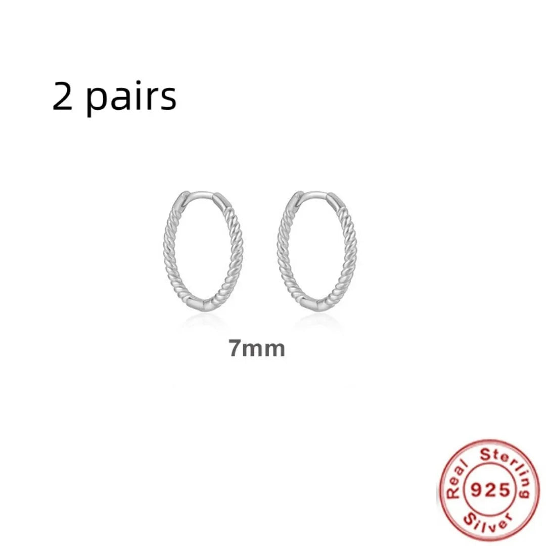 A pair of twisted sterling silver round earrings in a geometric design on a white background.