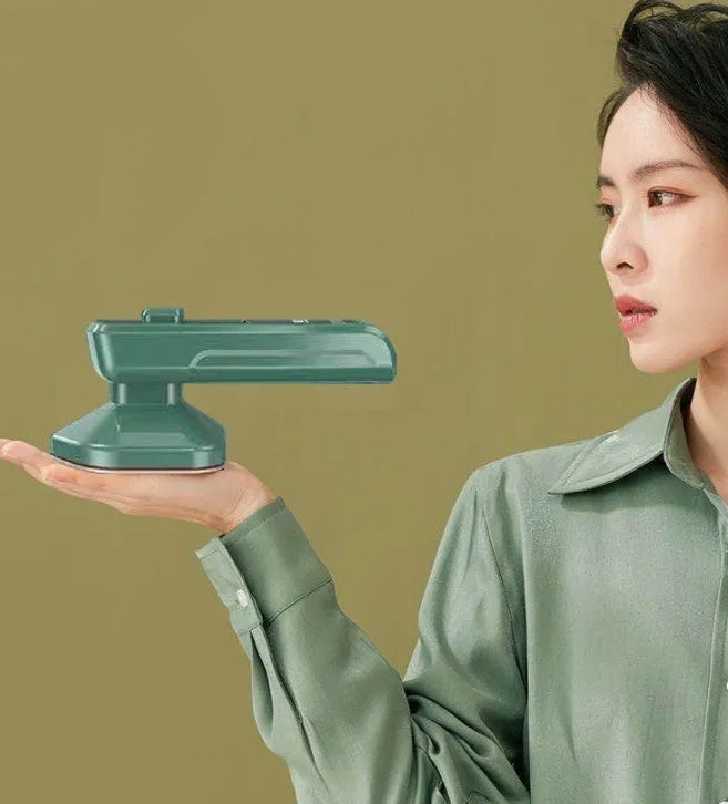 Dark green portable hand-held hanging steam ironing machine with a ceramic panel, shown with a power plug.
