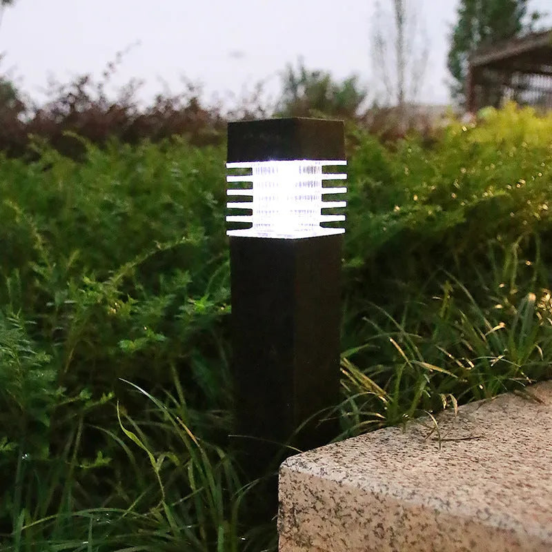 White cuboid solar-powered ground lamp for garden pathways with a solar panel on top.