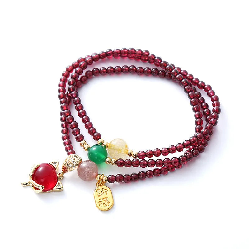 Purplish red garnet fox charm bracelet with adjustable rope on a wrist.