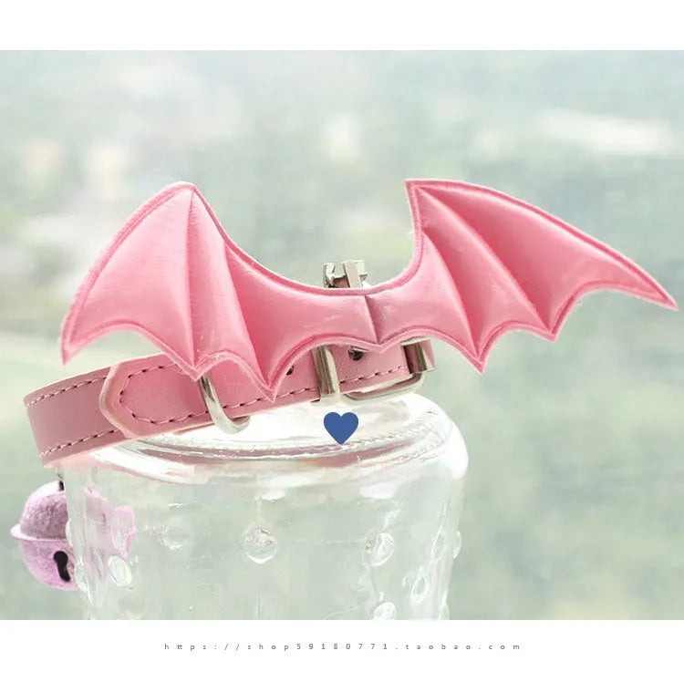 Small black patent leather dog collar with decorative devil wings design on a white background.