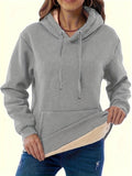 A women's loose fit hooded sweater in thick grey polyester with side pockets and long sleeves.