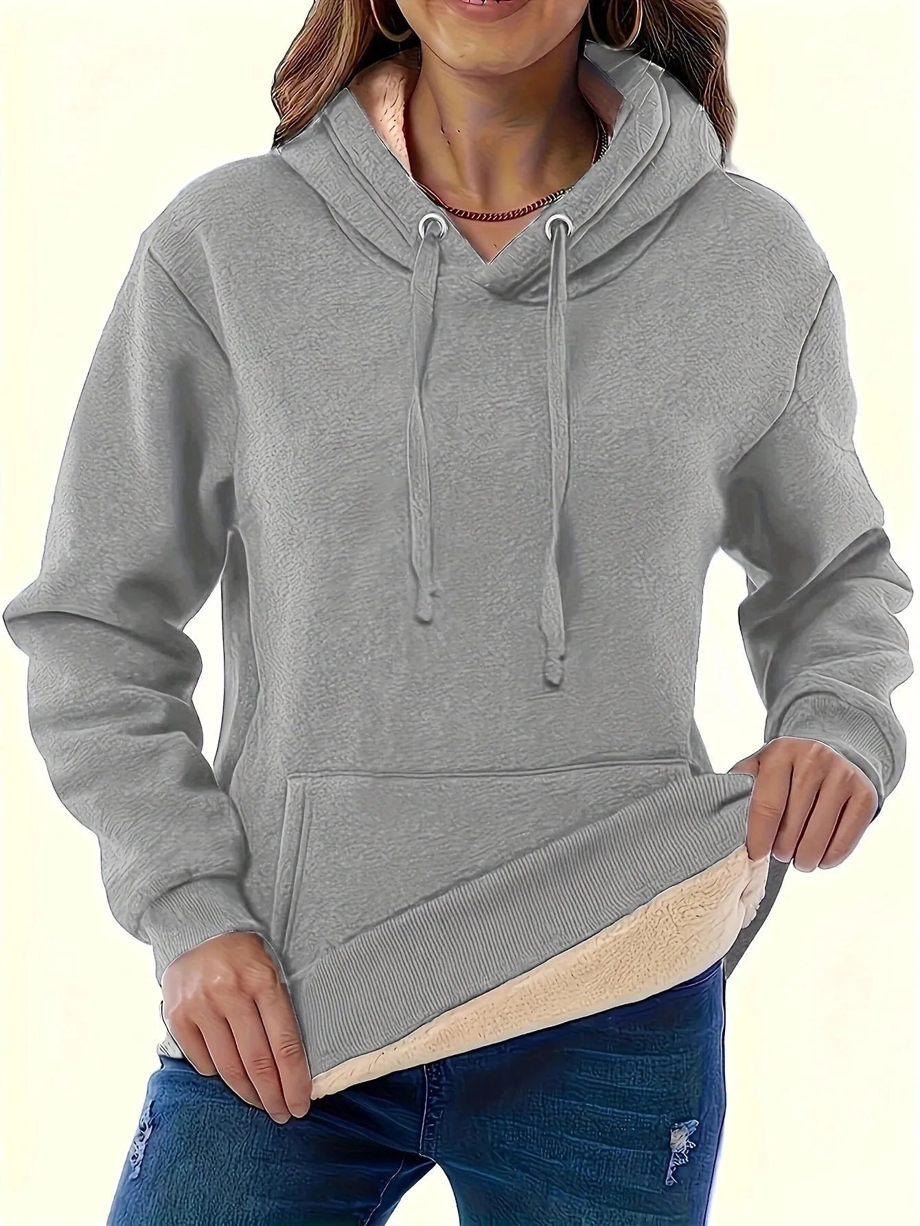 A women's loose fit hooded sweater in thick grey polyester with side pockets and long sleeves.