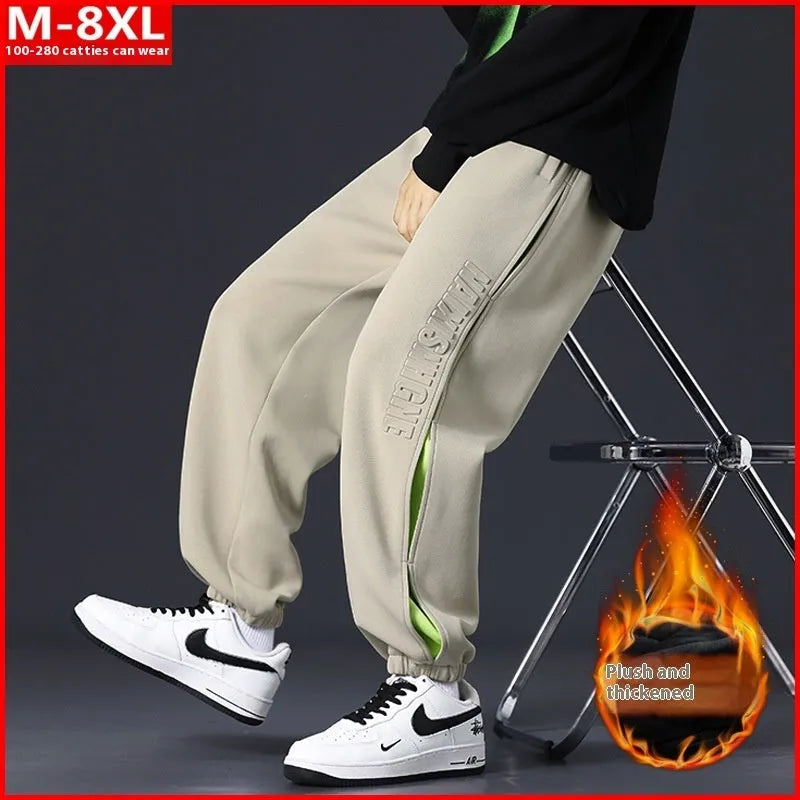 Man wearing loose grey-green cotton trousers with banded ankles and stitching detail.