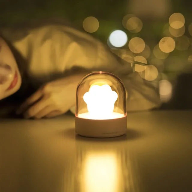 Pink and grey cat paw shaped USB night light with a music box feature on a desktop.
