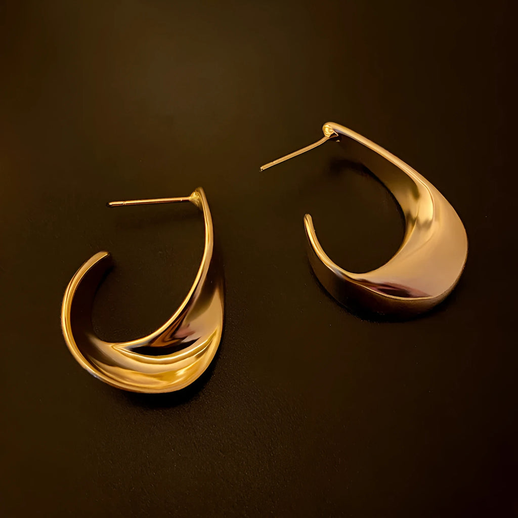 Twisted geometric metal earrings with electroplated gold finish and round design elements