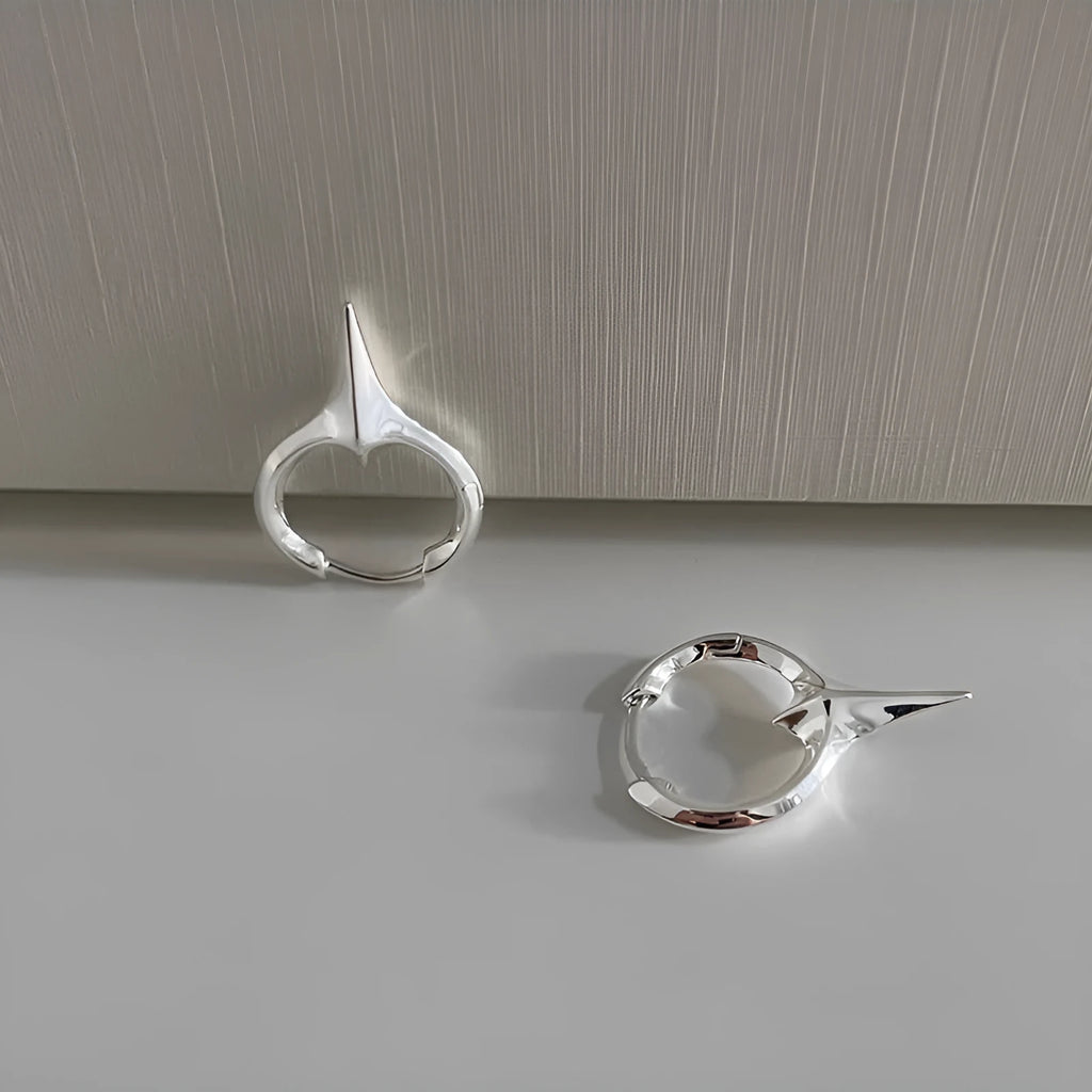 A pair of platinum-coloured geometric star-shaped ear clips for women on a white background.