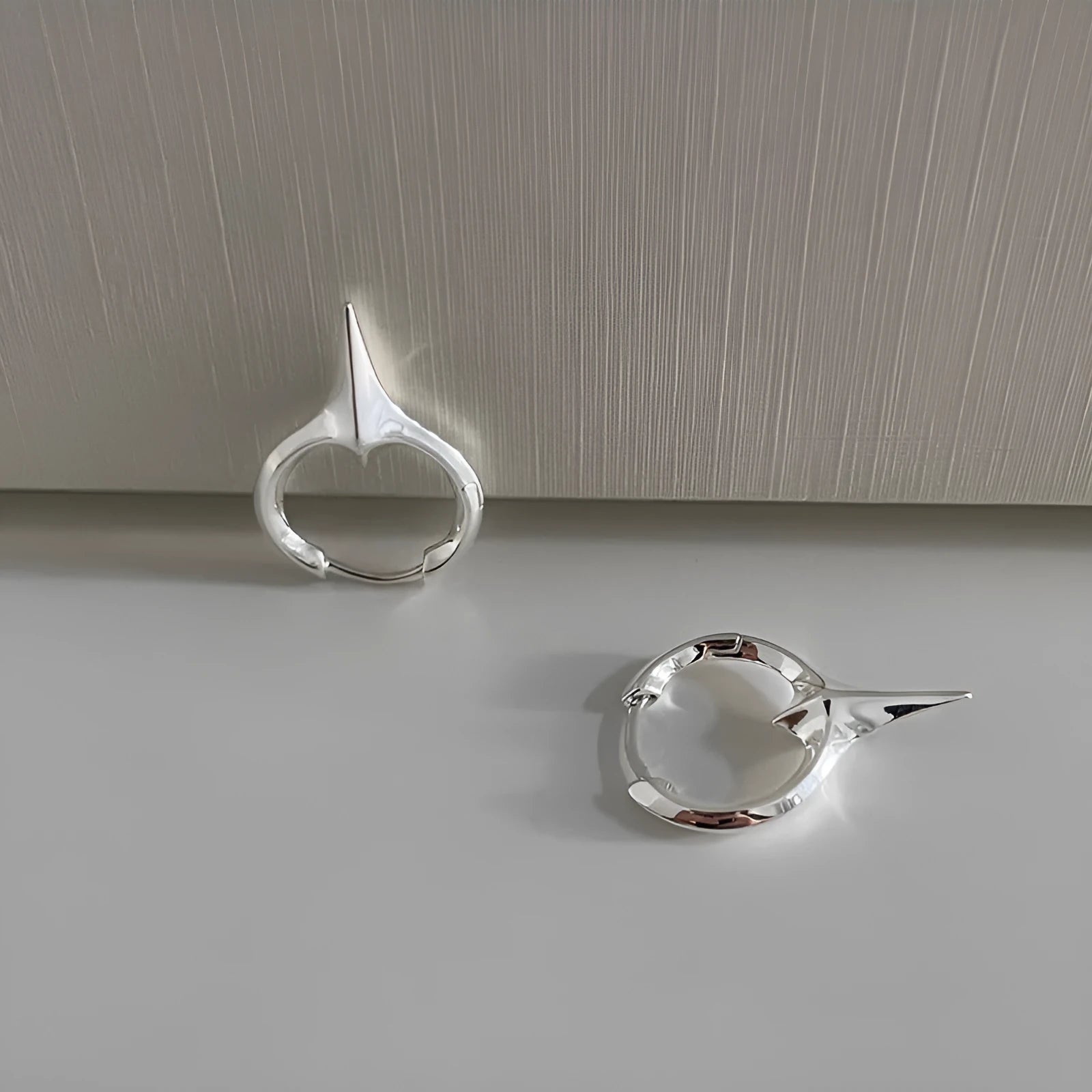 A pair of platinum-coloured geometric star-shaped ear clips for women on a white background.