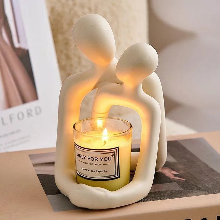 Modern loving couple resin statue in gold or milky white on a wooden shelf.