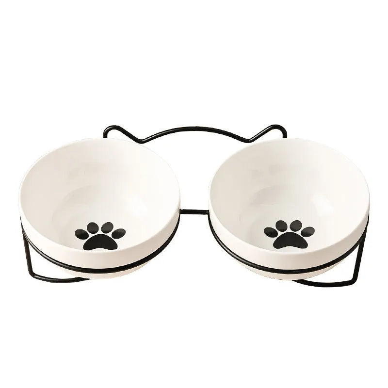 White ceramic cat bowl with decorative pattern sitting in a black iron frame stand.