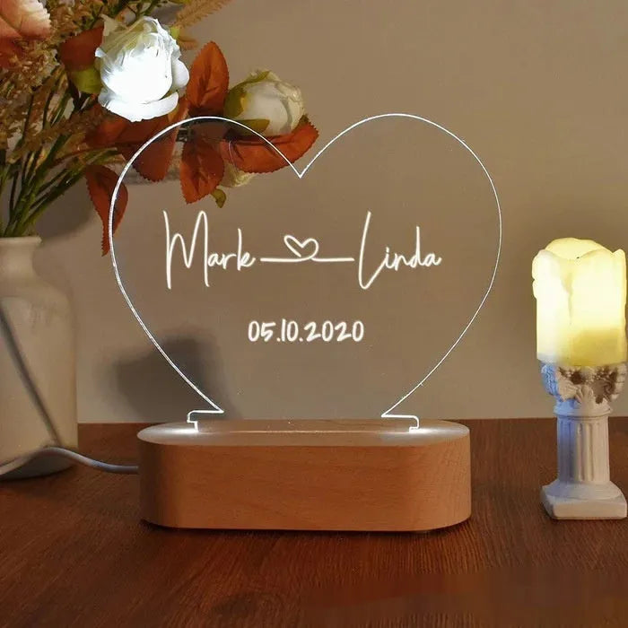 Custom transparent acrylic night light with engraved names and date, lit by LED base.