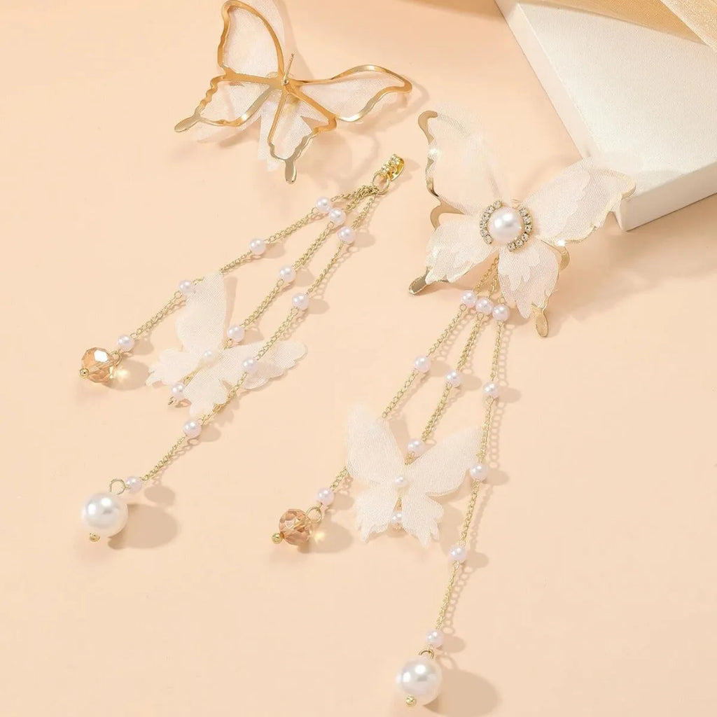 Close-up of white butterfly-shaped earrings with dangling lace tassels, pearl beads, and clear rhinestone accents.