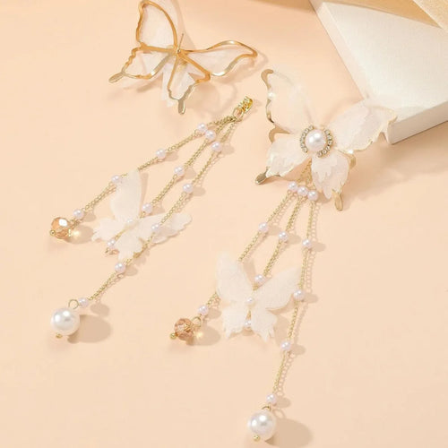 Close-up of white butterfly-shaped earrings with dangling lace tassels, pearl beads, and clear rhinestone accents.