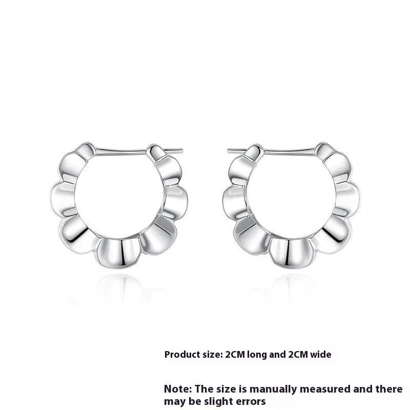 A pair of sterling silver geometric earrings with round details on a simple background.