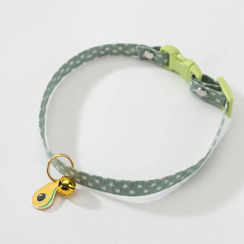 Green adjustable cat collar with a metal bell pendant and a matching bow tie on a white background.