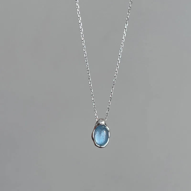 Geometric navy blue water drop pendant necklace on a model, showing the adjustable cross chain.