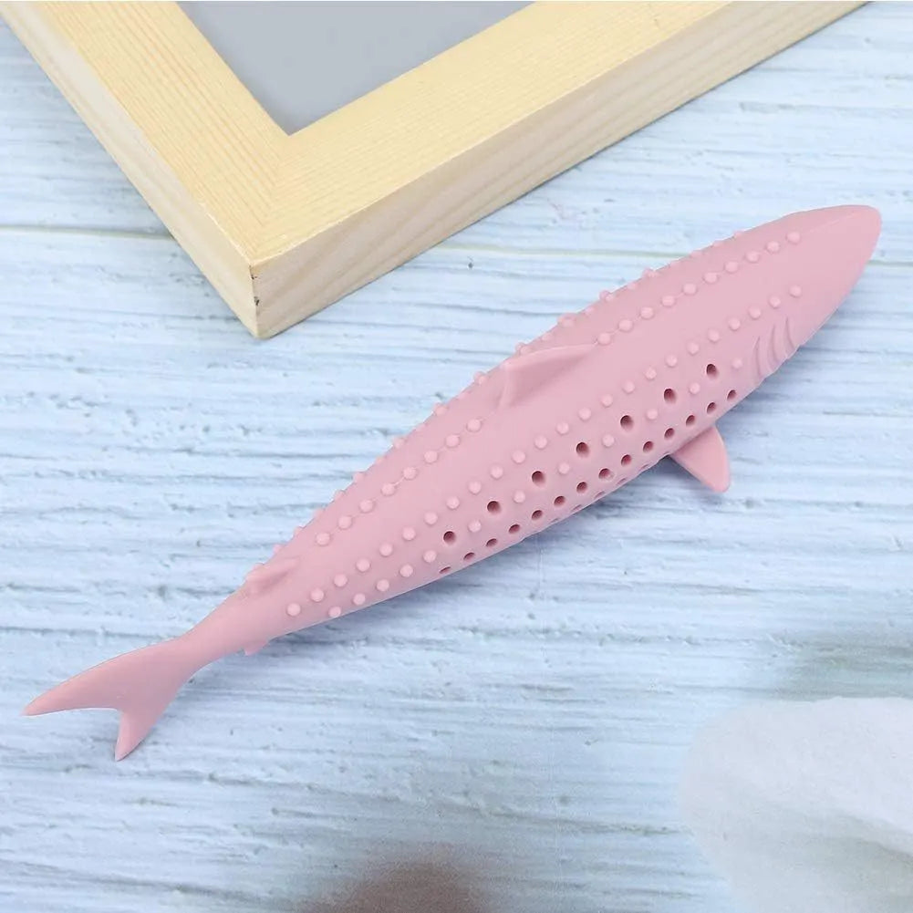 Green silicone fish-shaped cat chew toy with breathable side holes on wooden floor