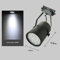 Black aluminium LED track spotlight with sliding head mounted on a track for wall lighting.