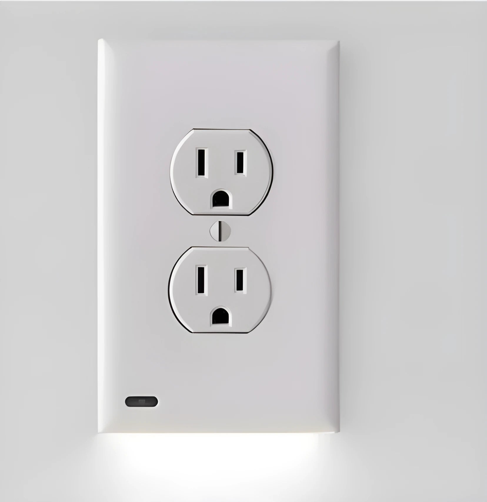 White plug-in LED night light with automatic sensor installed in a wall socket.