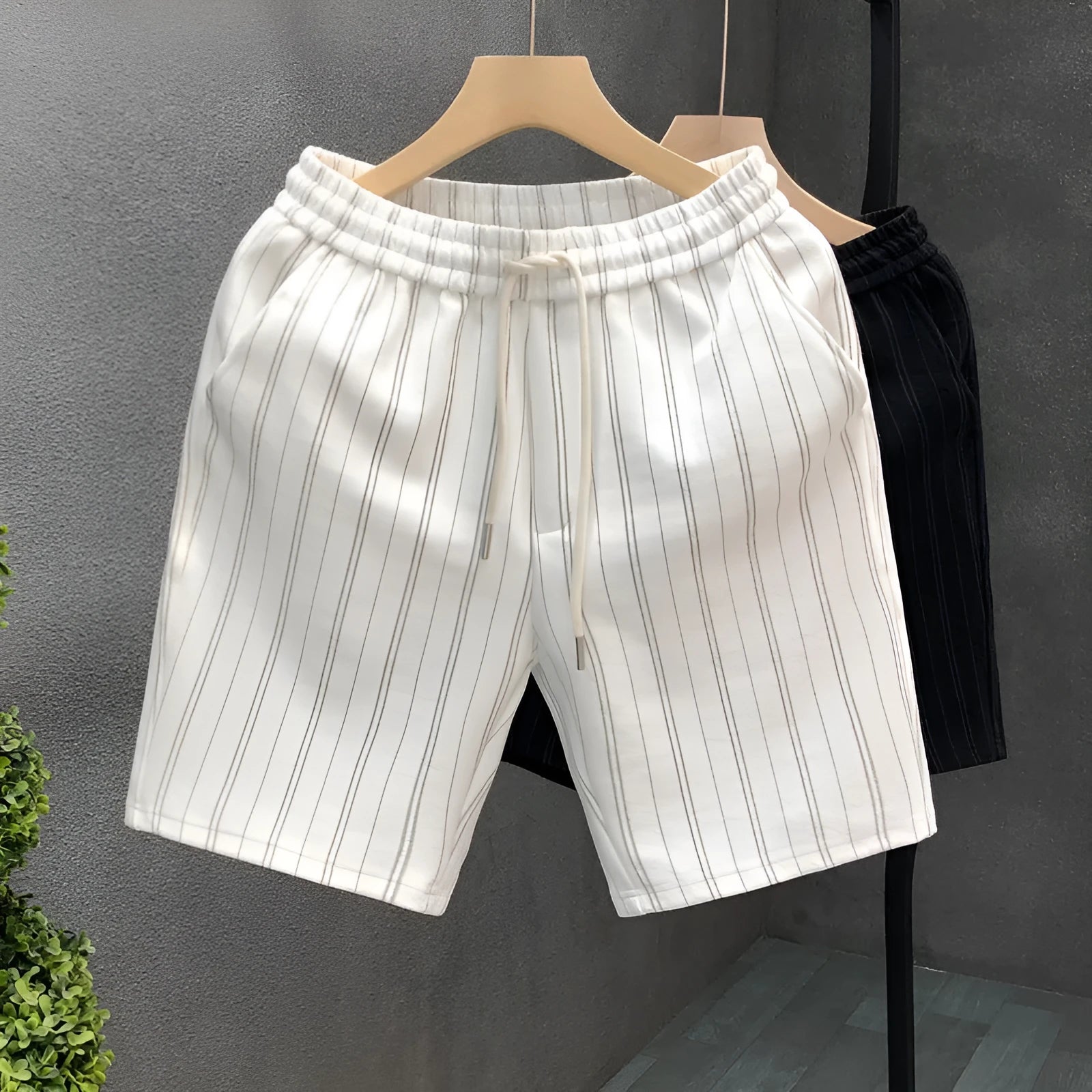 Man's black and white striped casual shorts with elastic waistband on a plain background.