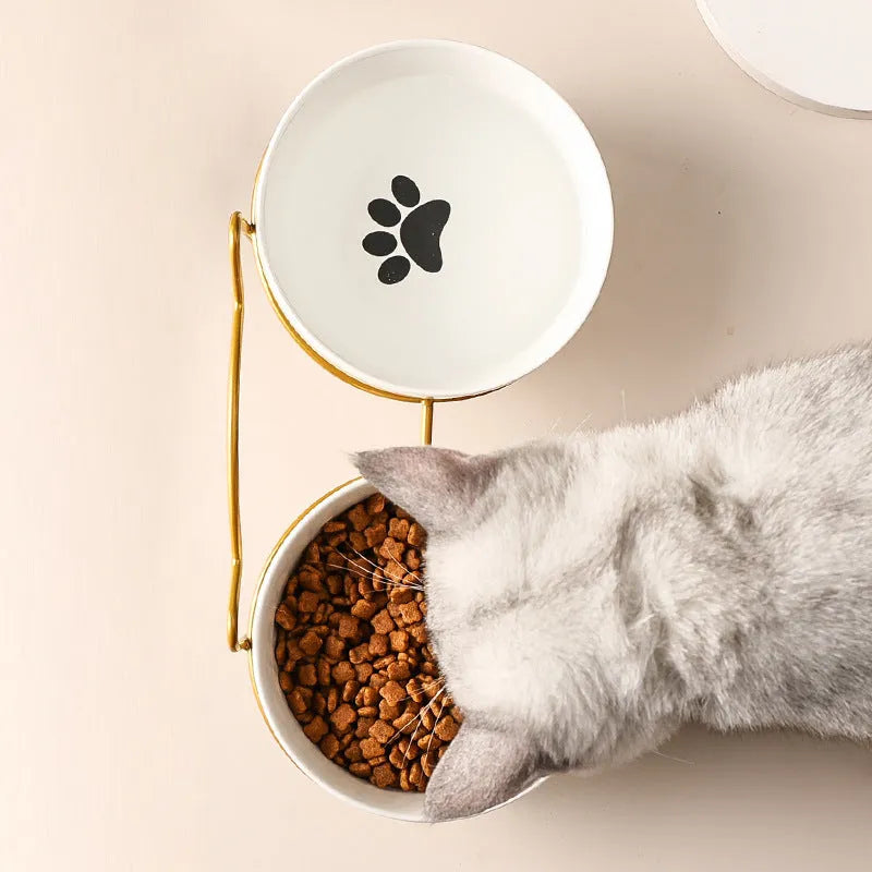 White ceramic cat bowl with decorative pattern sitting in a black iron frame stand.