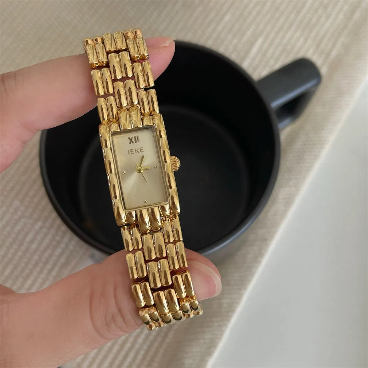 Women's bracelet-style watch with 15mm dial, silver stripe strap, and butterfly clasp